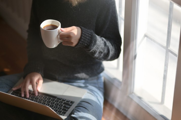 Woman Using Laptop While Holding A Cup of Coffee.jpg